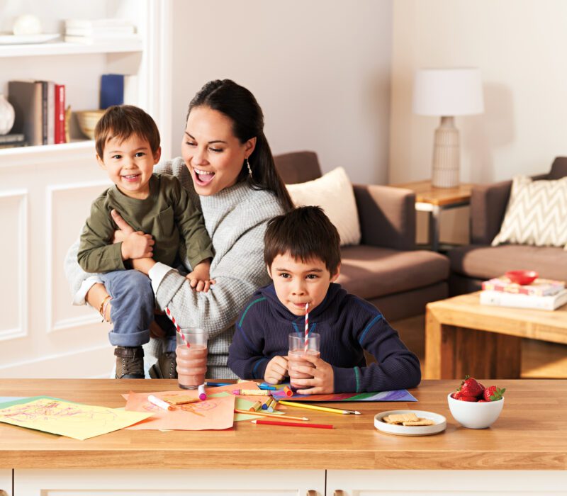 Parent and children sharing milk at the kitchen table